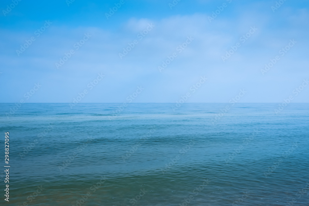 Beautiful white clouds on blue sky over calm sea with sunlight reflection, Bali Indonesia. Tranquil sea harmony of calm water surface. Sunny sky and calm blue ocean.