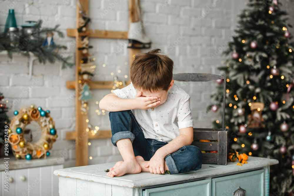 A boy sits in the kitchen on Christmas New Year A boy sits in the kitchen on Christmas New Year