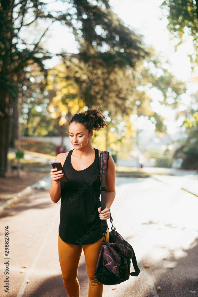 Portrait of young sporty woman using phone outdoors. Beautiful woman in sportswear. Portrait of young sporty woman using phone outdoors. Beautiful woman in sportswear.