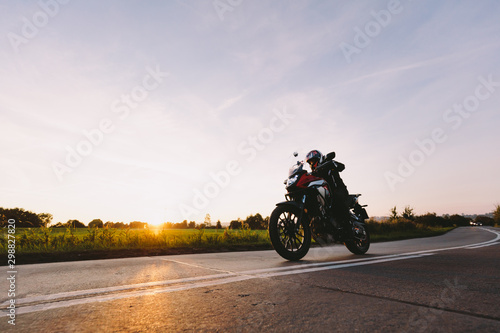 Fast motorcycle drive on asphalt road at sunset.