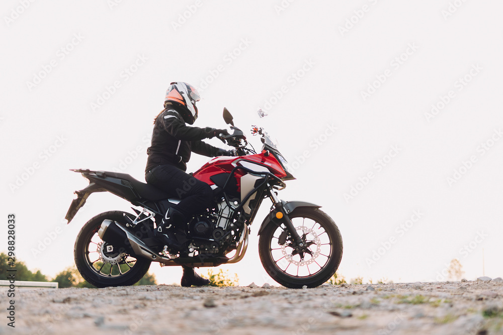Woman standing on roadside with a motorbike. Motorcycle trip Woman standing on roadside with a motorbike. Motorcycle trip