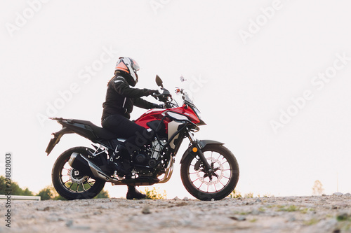 Fototapeta Naklejka Na Ścianę i Meble -  Woman standing on roadside with a motorbike. Motorcycle trip