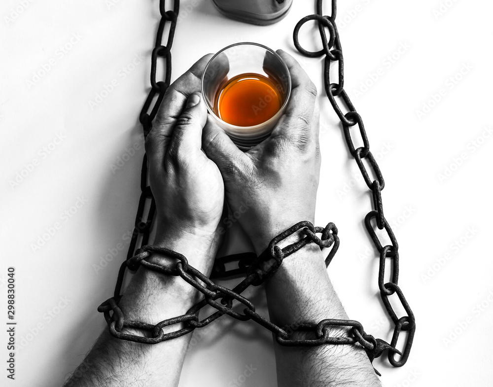 Man's hands in old rusty chains near the bottle. Addicted to alcohol. Dangerous habit.