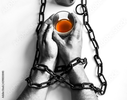 Man's hands in old rusty chains near the bottle. Addicted to alcohol. Dangerous habit. photo