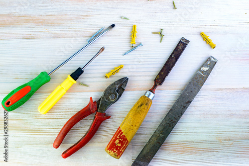 Repair tools on a wooden light background: file, pliers, pliers, screwdriver, screws, bolts