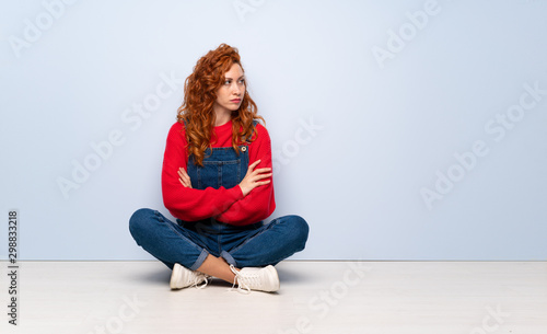 Redhead woman with overalls sitting on the floor portrait