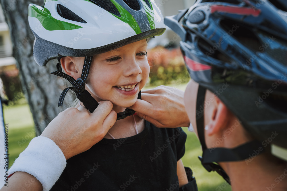 © Yakobchuk Olena - Loving mother helping her daughter to put on bicycle helmet © Yakobchuk Olena - Loving mother helping her daughter to put on bicycle helmet