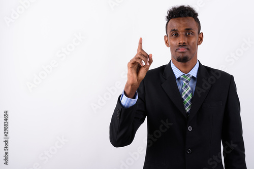 Young bearded African businessman wearing suit against white bac