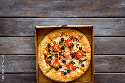 Order pizza to home or office. Italian food in box on dark wooden background top view copy space