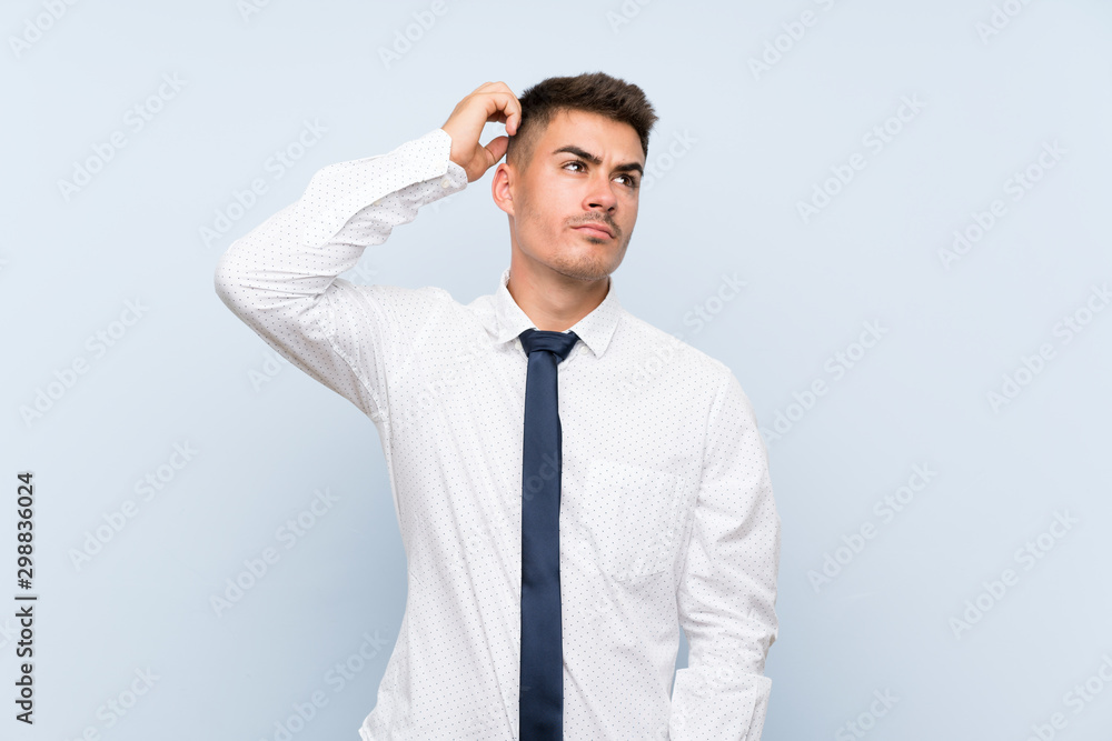 Handsome businessman over isolated blue background having doubts and with confuse face expression Handsome businessman over isolated blue background having doubts and with confuse face expression