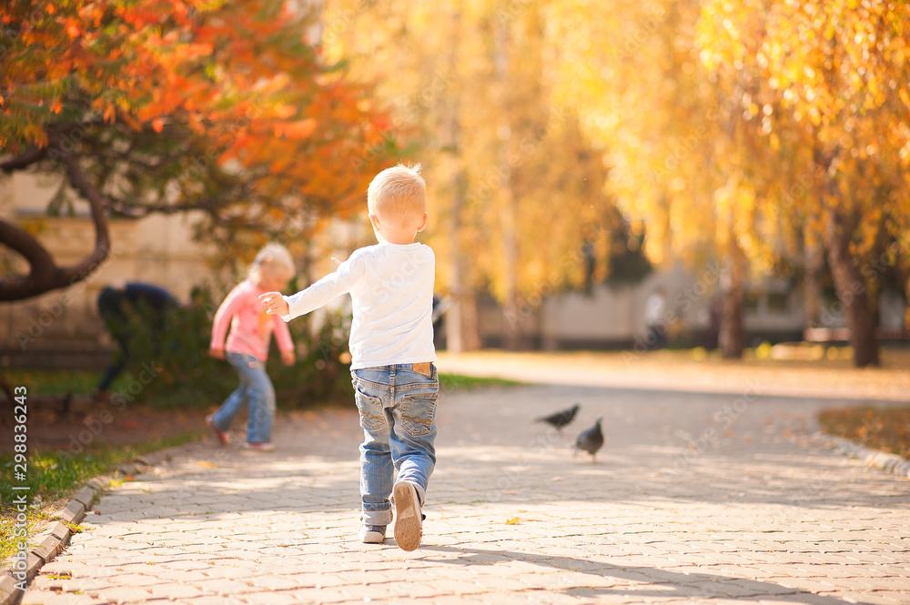 Happy children play in the park closeup. Boy and girl run and have fun in the autumn in the sun and copy space. Happy childhood moments. Happy children play in the park closeup. Boy and girl run and have fun in the autumn in the sun and copy space. Happy childhood moments.