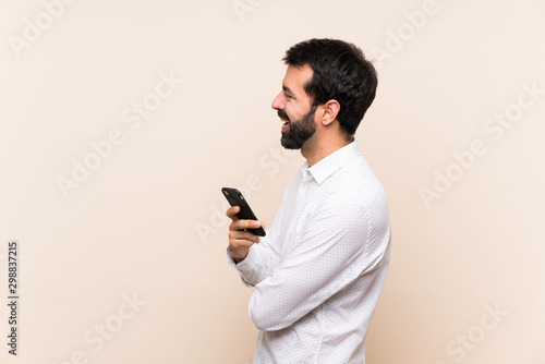 Fotografie Young man with beard holding a mobile in lateral position