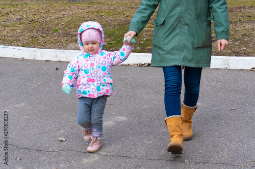 Litle girl holding woman hand and walking outdoor