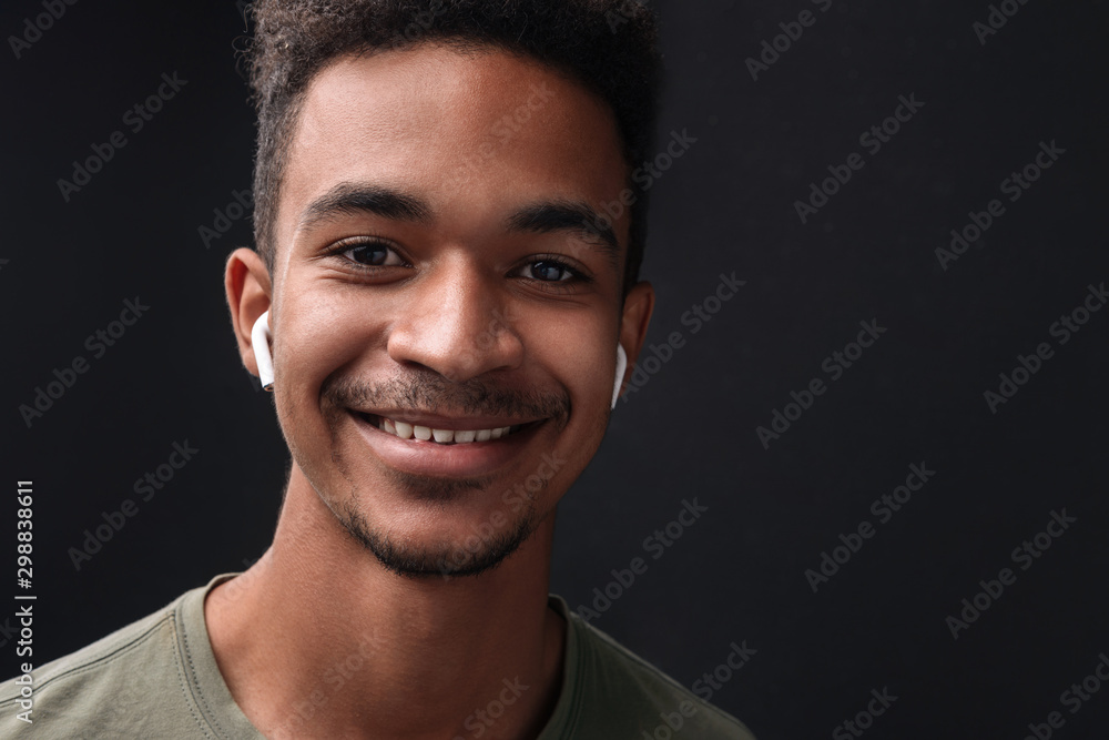 Obraz premium Image of smiling african american guy using earpods