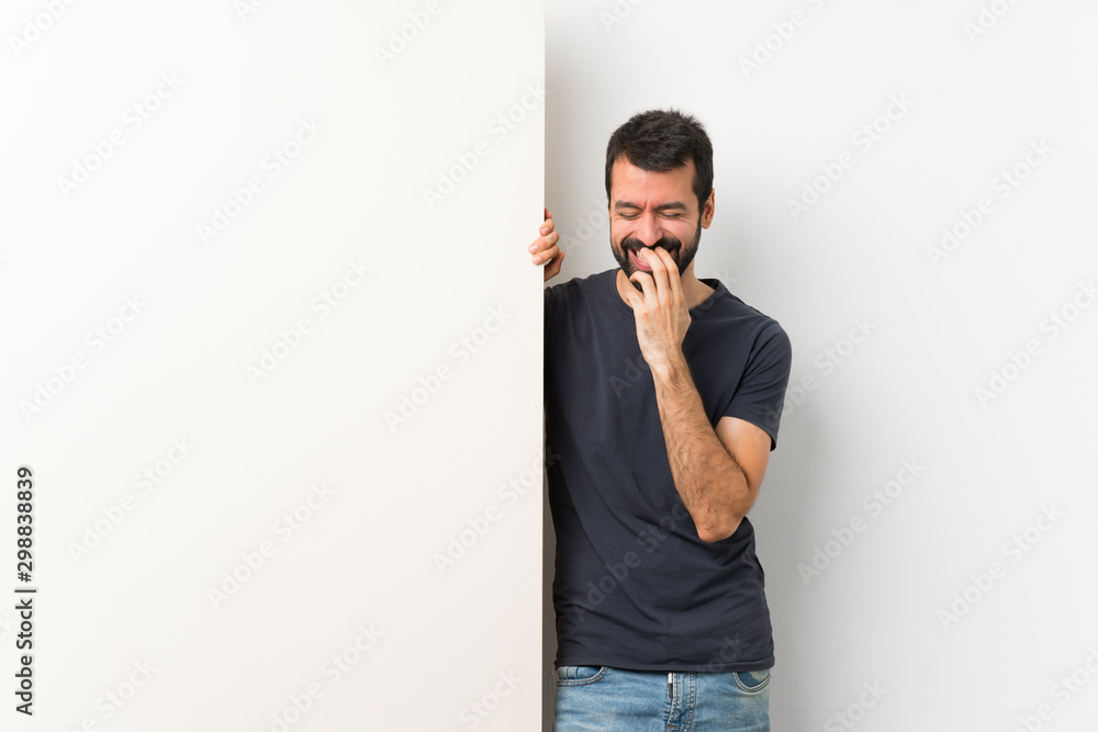 Young handsome man with beard holding a big empty placard smiling a lot Young handsome man with beard holding a big empty placard smiling a lot