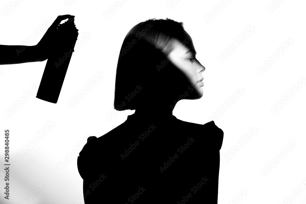 Black and white silhouette portrait with shadow and spot of light. The girl uses hairspray. Hair cosmetic concept.