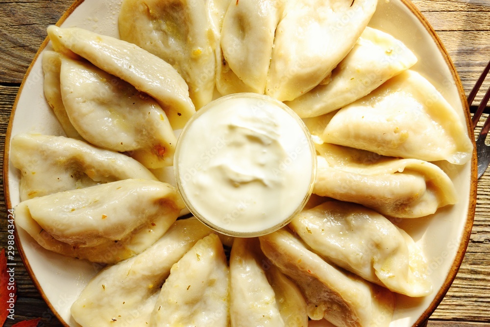 Dumplings in a beautiful plate. Dumplings on a wooden background. Wooden table background with autumn leaves. Appetizing little pie with filling. Traditional homemade food. Dumplings in a beautiful plate. Dumplings on a wooden background. Wooden table background with autumn leaves. Appetizing little pie with filling. Traditional homemade food.