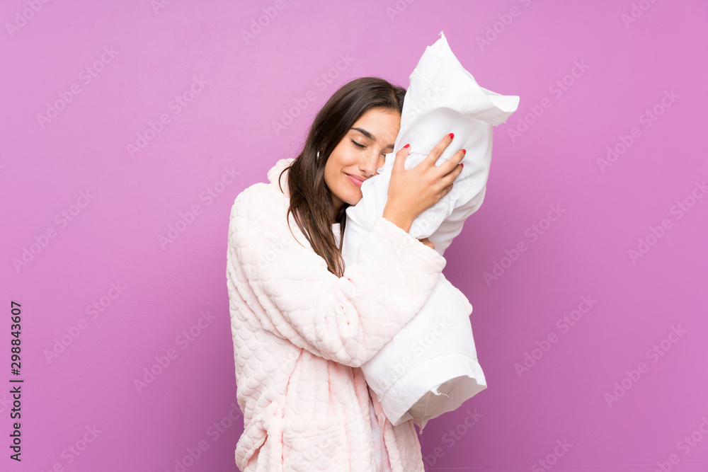 Young woman in pajamas and dressing gown over isolated purple background Young woman in pajamas and dressing gown over isolated purple background