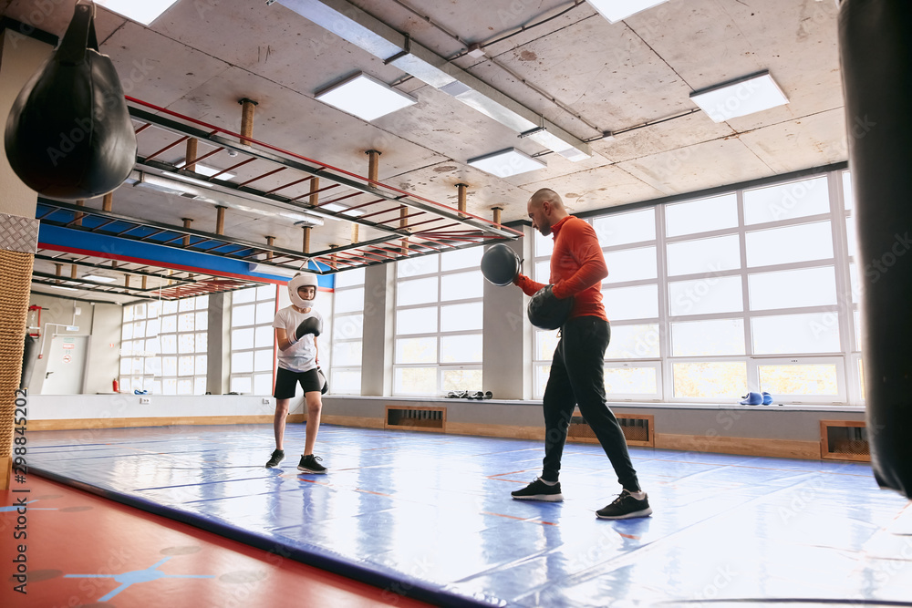 Fototapeta premium little boy and his personal coach working out at gym, full length side view photo. copy space, lifestyle, free time, spare time