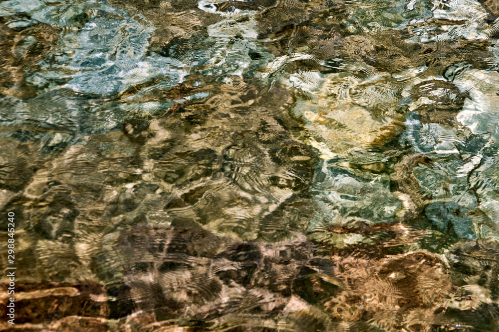 Clear creek water with stones at the bottom. Background of stones. Pebbles under water texture. Underwater in spring water, close-up. Clear creek water with stones at the bottom. Background of stones. Pebbles under water texture. Underwater in spring water, close-up.