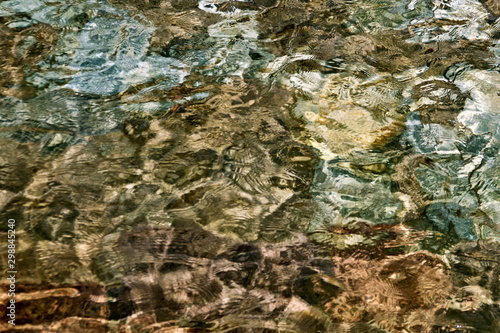 Clear creek water with stones at the bottom. Background of stones. Pebbles under water texture. Underwater in spring water, close-up.