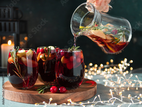 Papier peint Female hand pours winter sangria in glasses with fruit slice, cranberry and rosemary
