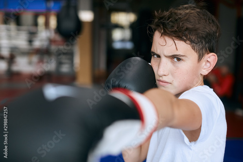 agressive angry boy punching with boxing gloves.close up cropped photo. blurred foreground.