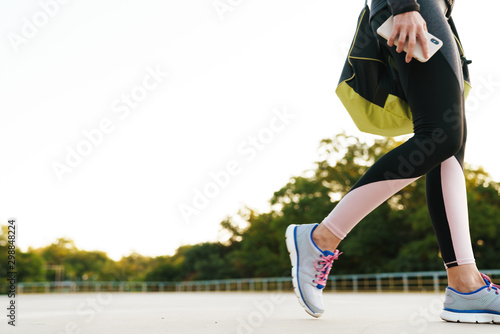 Cropped image of slim woman walking with sport bag for workout outdoors