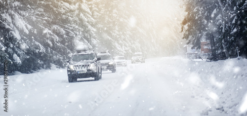 Winter road in beatiful forest. Snow calamity or blizzard. Fast cars on snowy roads in storm. © Milan