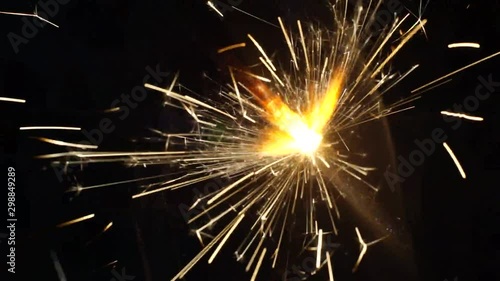 Phuljhadi or sparklers being lit from a candle against a dark background on the hindu festival of diwali photo