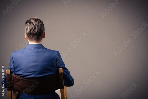 Rear view of man sitting against the wall.