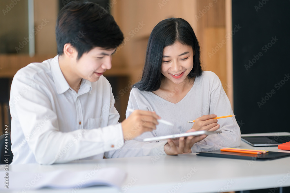 Young Asian couple or college student using digital tablet and laptop computer notebook work together at coffee shop or university campus. Young Asian couple or college student using digital tablet and laptop computer notebook work together at coffee shop or university campus.