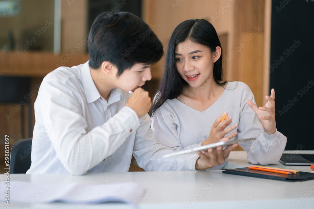 Young Asian couple or college student using digital tablet and laptop computer notebook work together at coffee shop or university campus. Young Asian couple or college student using digital tablet and laptop computer notebook work together at coffee shop or university campus.