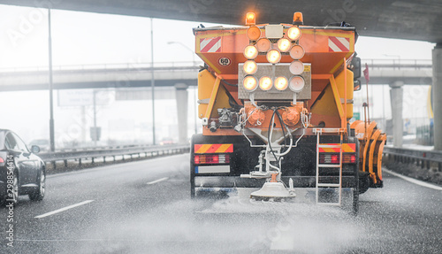 Fotografie Snow plow salting street in winter time