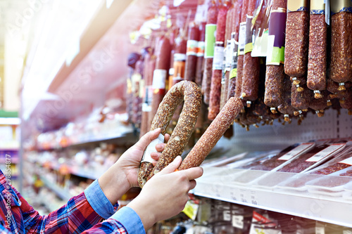 Woman with smoked sausage in store