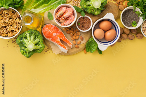 Omega 3 food sources and omega 6 on yellow background top view. Foods high in fatty acids including vegetables, seafood, nut and seeds
