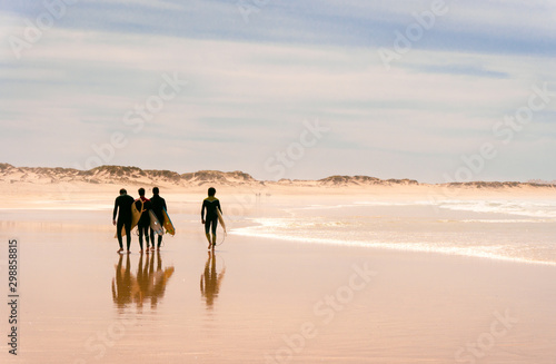 A group of surfers walks along the ocean beach. sunny. photo