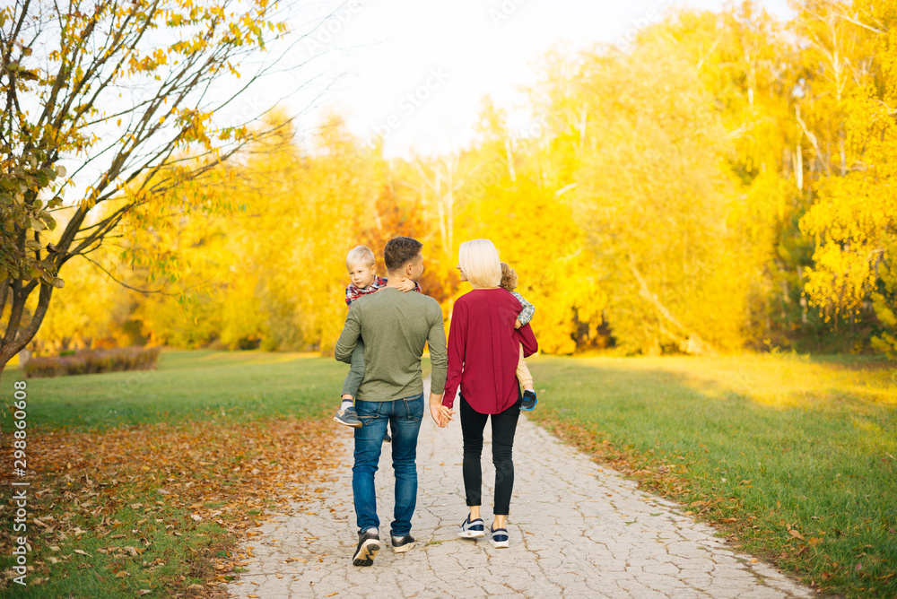Young happy family with two little boys walking in autumn colorful park Young happy family with two little boys walking in autumn colorful park