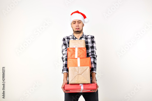 Holidays and presents concept - Funny man in Christmas hat holding many gift boxes on white background with copyspace