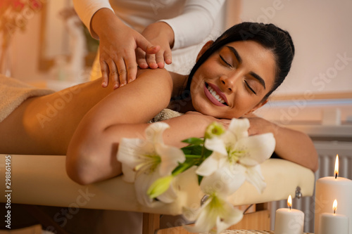 Dark hair pretty young woman on massage table enjoying her treatment and smiling 