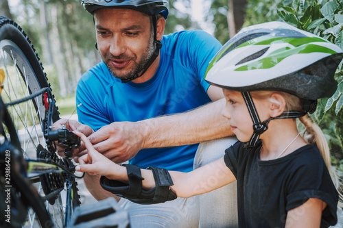 Little girl helping her father to repair bicycle wheel