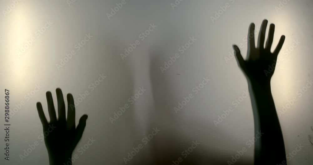 Close-up shadows of a woman's hands and silhouette reflected behind the glass. Close-up shadows of a woman's hands and silhouette reflected behind the glass.