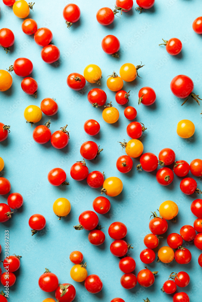 Red and yellow cherry tomatoes on blue background. Fresh bright organic vegetables. Red and yellow cherry tomatoes on blue background. Fresh bright organic vegetables.