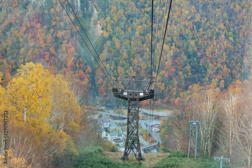 Aerial view from a cable car of Kurodake Ropeway flying over colorful autumn forests with seasonal colorful trees and landscape in Japan. Nature and outdoor concept. photo