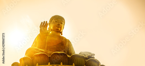 Fotografi Large Buddha in bleaseing position with ligjht warm sunlight sky bsckground, Tia