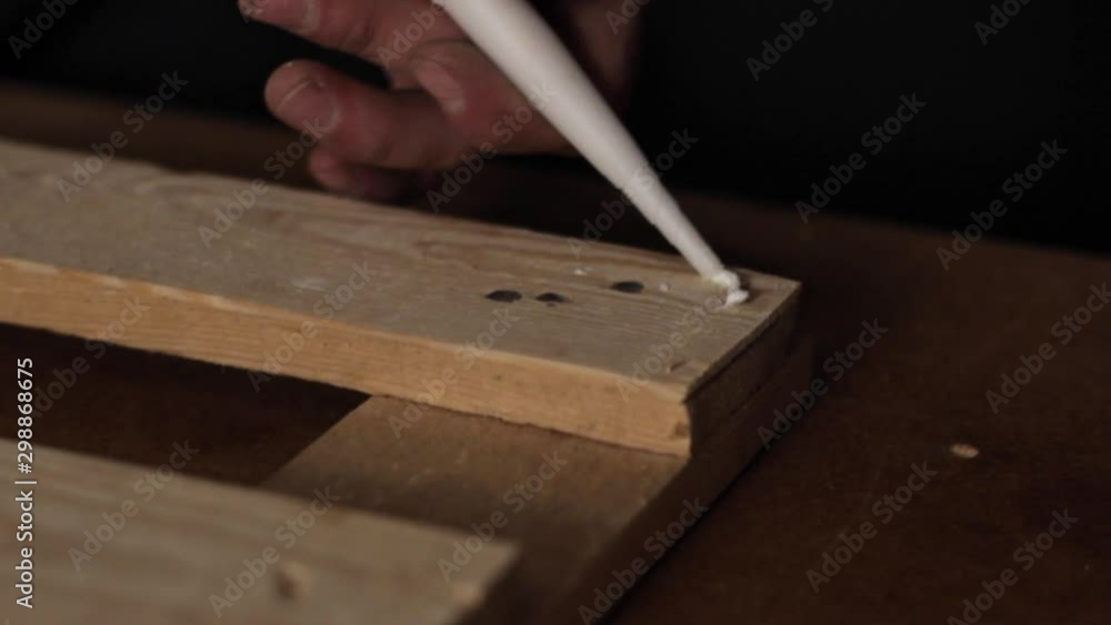 Wood furniture adhesive being applied to a polished wooden plank, close follow shot Wood furniture adhesive being applied to a polished wooden plank, close follow shot