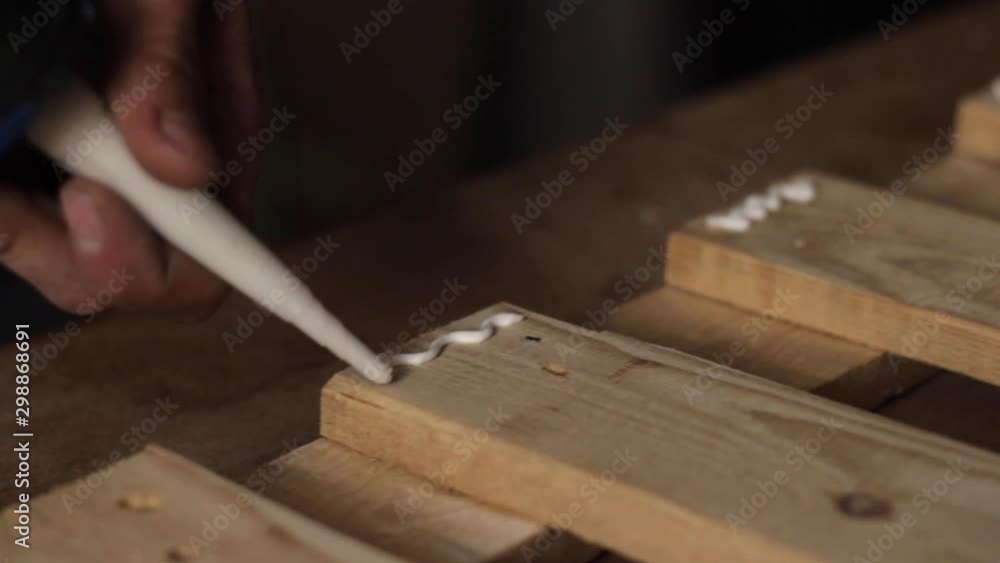 Wood adhesive glue being applied in patterns on wooden furniture planks, closeup Wood adhesive glue being applied in patterns on wooden furniture planks, closeup