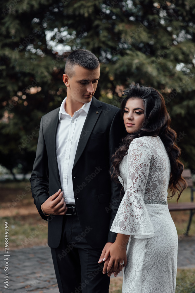 The guy in the suit and the girl in white dress embracing. A man and woman who loved each other. A love story. Romantic moment. Young beautiful couple in love, love, pre-wedding photo shoot. The guy in the suit and the girl in white dress embracing. A man and woman who loved each other. A love story. Romantic moment. Young beautiful couple in love, love, pre-wedding photo shoot.