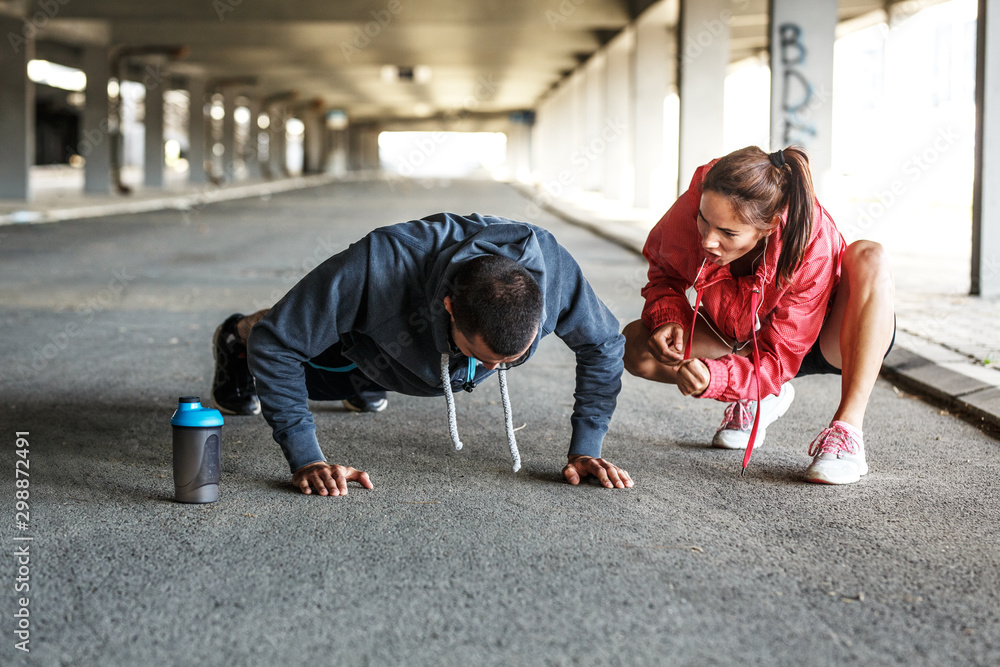 Young man doing push ups while his girlfriend cheers and push him to the limit. Young man doing push ups while his girlfriend cheers and push him to the limit.