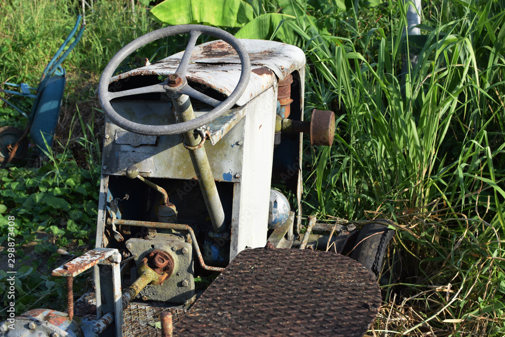 Wasted dilapidated rustic old farm tractor left on the vicinity of agricultural college campus. close up Wasted dilapidated rustic old farm tractor left on the vicinity of agricultural college campus. close up